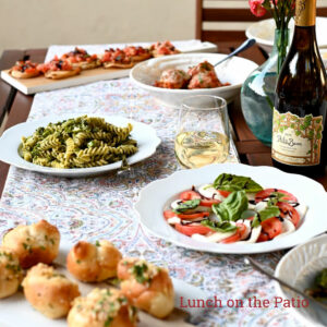 table with white table cloth that has plates of italian food and wine on it