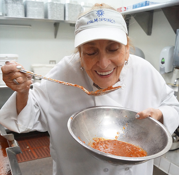 Maria smiling over a bowl of freshly prepared marinara sauce