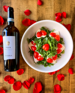 A bottle of wine laying next to the caprese salad